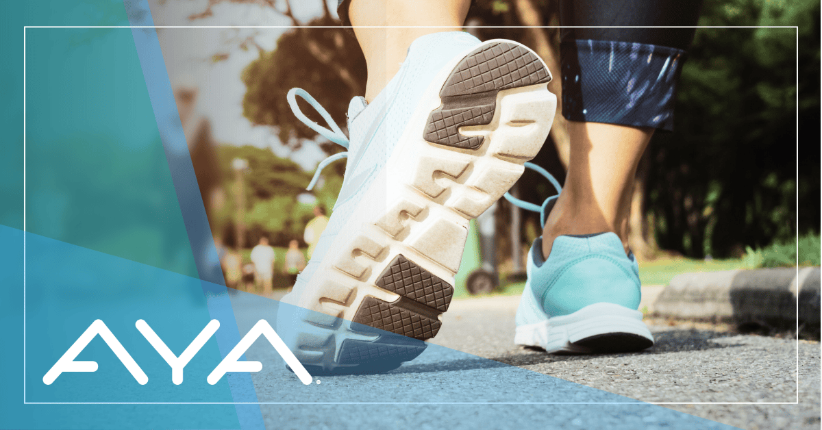 Athletic shoe mid-stride on paved path, showing white sneaker sole and teal companion shoe. Teal and blue geometric overlay on left side with white AYA logo. Natural sunlit background with trees. White border frames the image. Emphasizes movement and summer walking safety.