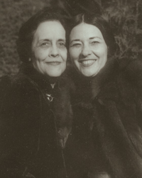 A black and white close-up portrait of two smiling women: Frances Davis, older with dark clothing, and Te Ata, younger with her dark hair parted in the middle, their warm expressions capturing their mentor-student bond.