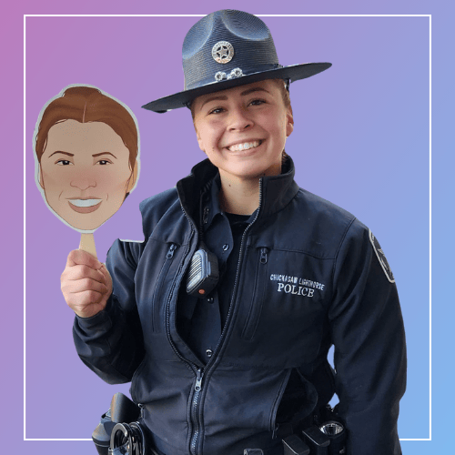 Officer Kaelee Langley of the Chickasaw Lighthorse Police smiles while holding up an illustrated avatar face she voiced for the AYA app. She wears a dark police uniform and traditional Lighthorse hat against a purple background